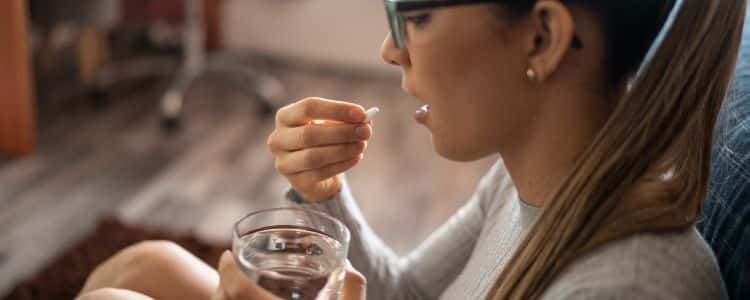 A woman swallowing a pill