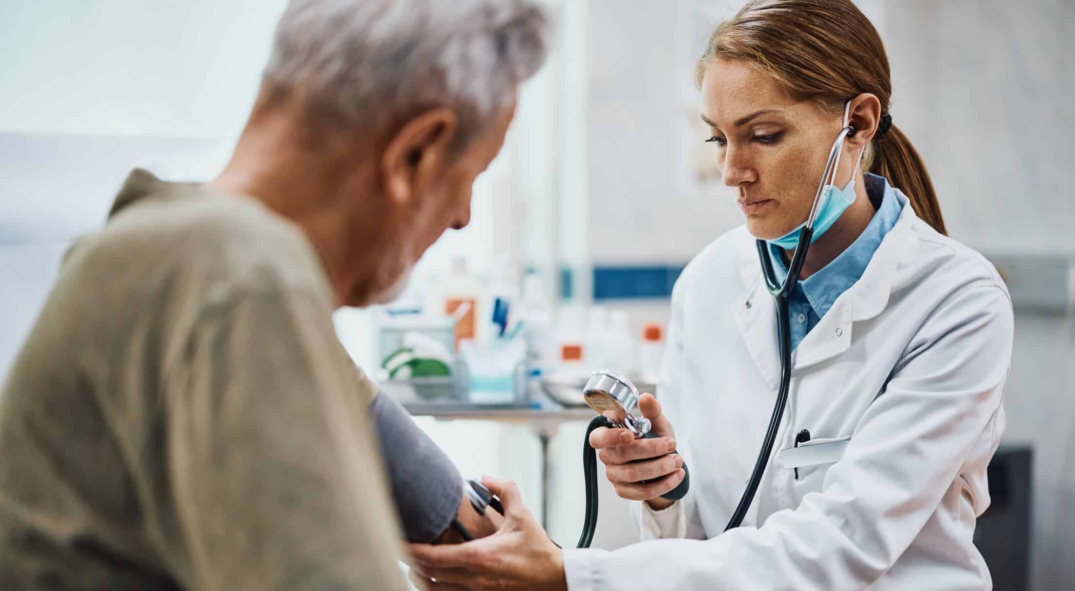 Female doctor measuring blood pressure of a patient during medical exam at doctor's office.