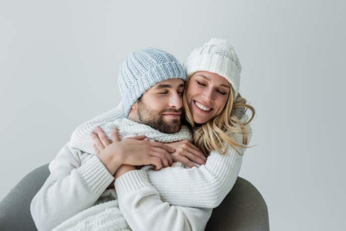 cheerful-woman-in-knitted-hat-hugging-joyful-boyfriend